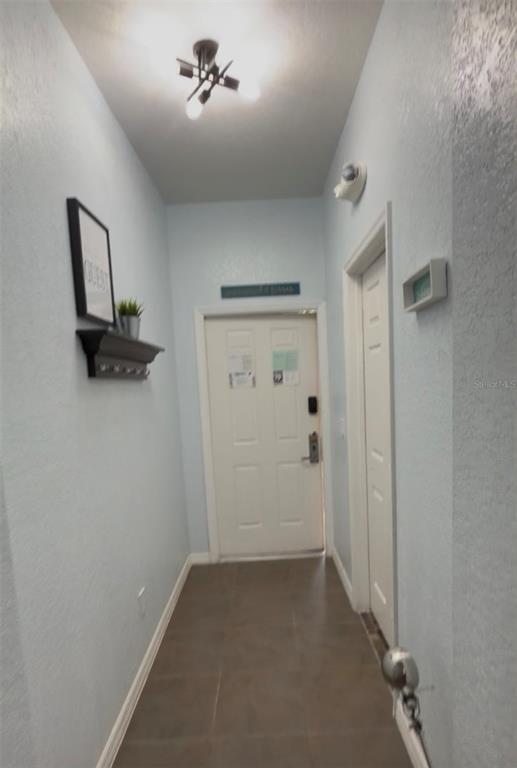 A narrow entryway features light blue walls, tile flooring, a ceiling light fixture, and a white door — 1337 CALABRIA AVENUE, DAVENPORT, FL