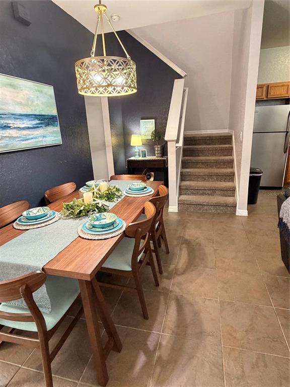 A dining area features a wooden table, chairs, a pendant light, and stairs leading upward — 1337 CALABRIA AVENUE, DAVENPORT, FL