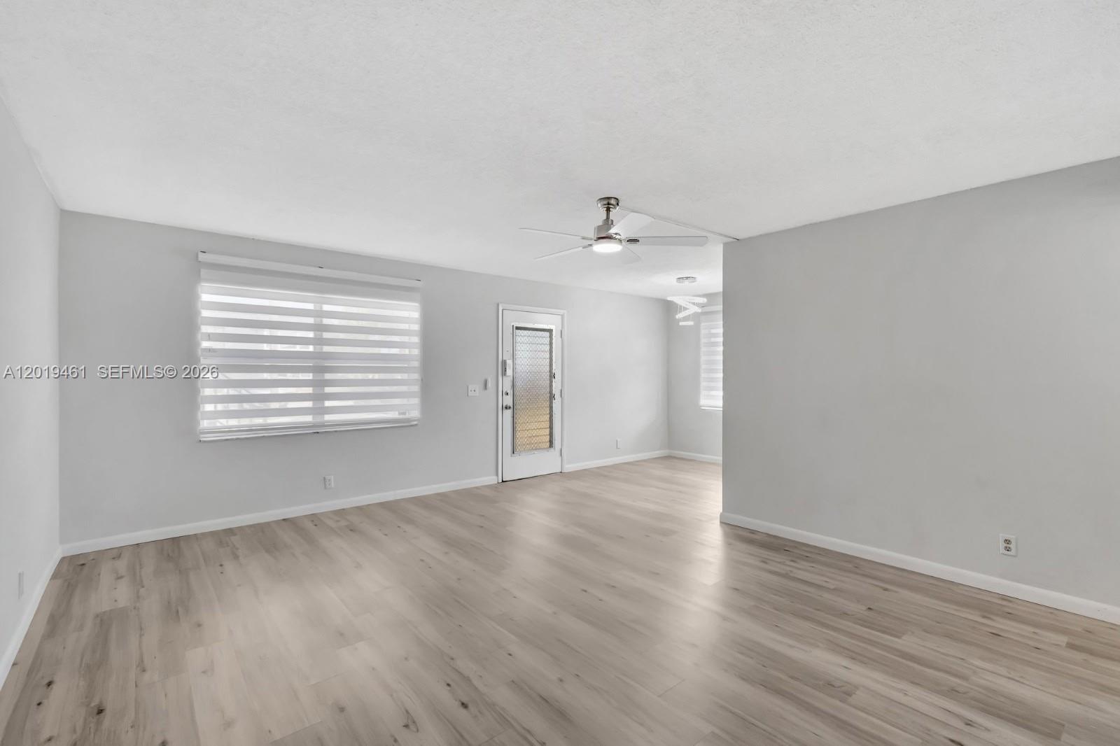 An empty living room features light gray walls, wood-look flooring, and a ceiling fan — 481 Burgundy K # K, Delray Beach FL 33484, DELRAY BEACH, FL
