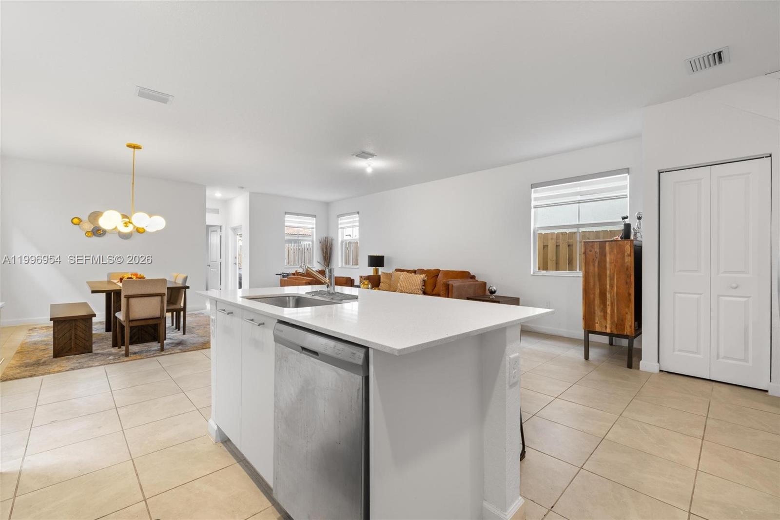 This open-concept kitchen features a white island with a stainless steel dishwasher and tile flooring — 2357 NW 130th St, Miami FL 33167, MIAMI, FL