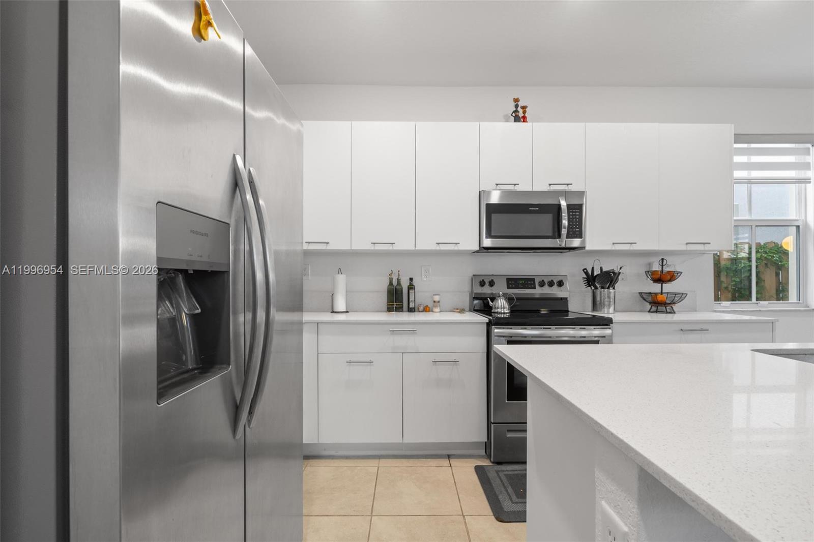 A modern kitchen features white cabinets, stainless steel appliances, and a white quartz countertop island — 2357 NW 130th St, Miami FL 33167, MIAMI, FL