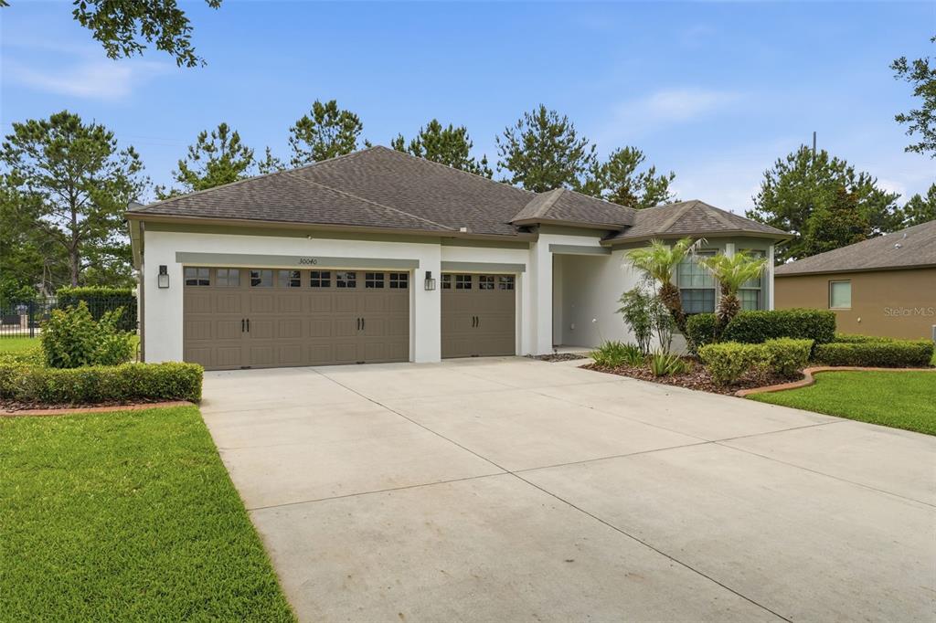 A single-story house with a three-car garage and a concrete driveway — 30040 DONNINGTON LOOP, MOUNT DORA, FL