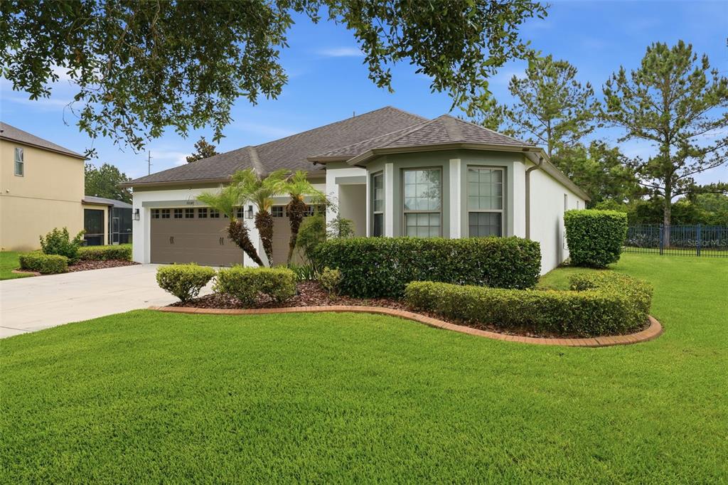 A single-story house with a two-car garage, a bay window, and landscaped front lawn — 30040 DONNINGTON LOOP, MOUNT DORA, FL