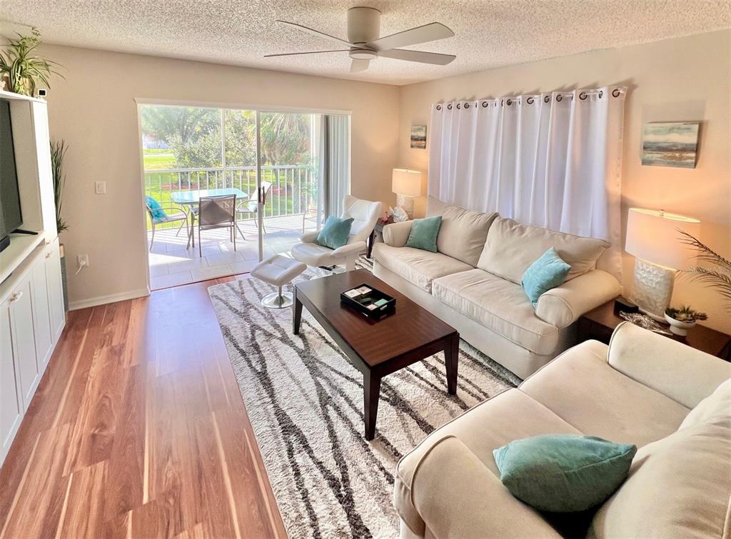 A living room features a beige sofa, a dark wood coffee table, and a sliding door — 6501 STONE RIVER ROAD UNIT 203, BRADENTON, FL