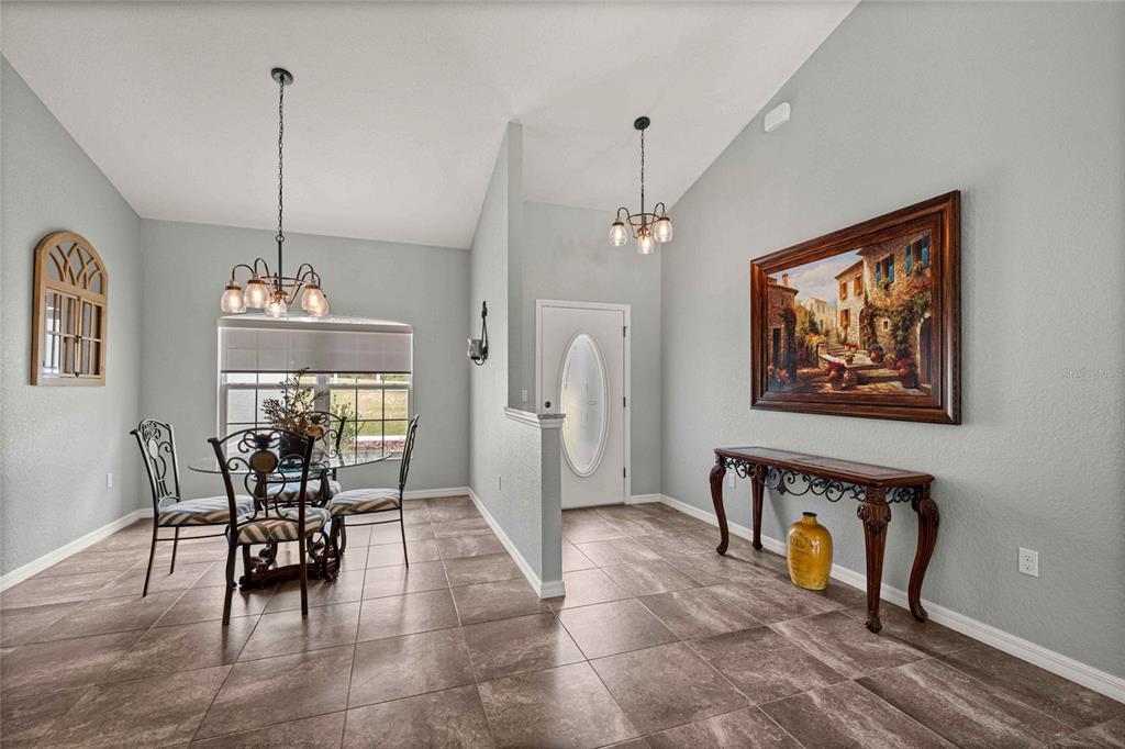 A dining area with tile floors, a glass table, and a console table near the entryway — 13130 SW 88TH STREET, DUNNELLON, FL