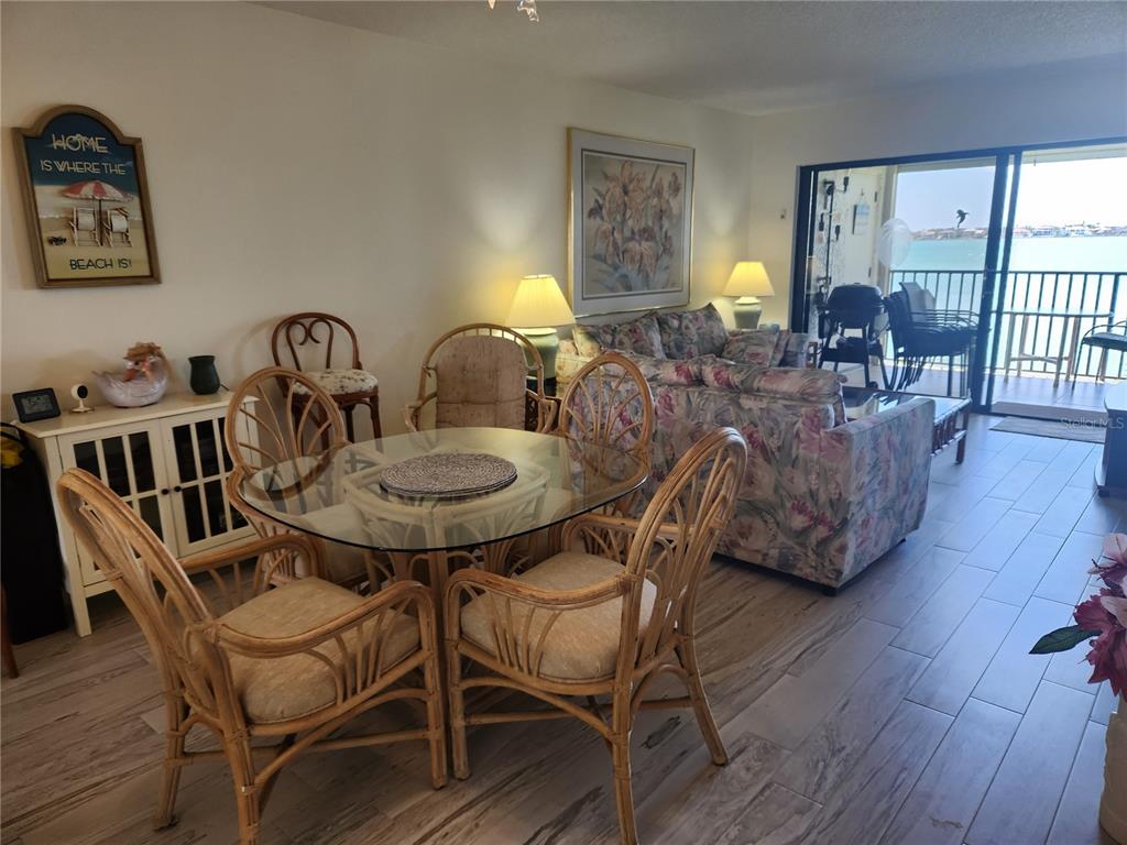 A dining area with a glass table and rattan chairs sits before a floral sofa — 6287 BAHIA DEL MAR CIRCLE UNIT 311, ST PETERSBURG, FL