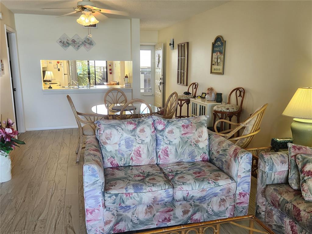 A living room with floral sofas, a dining area, and a kitchen pass-through window — 6287 BAHIA DEL MAR CIRCLE UNIT 311, ST PETERSBURG, FL