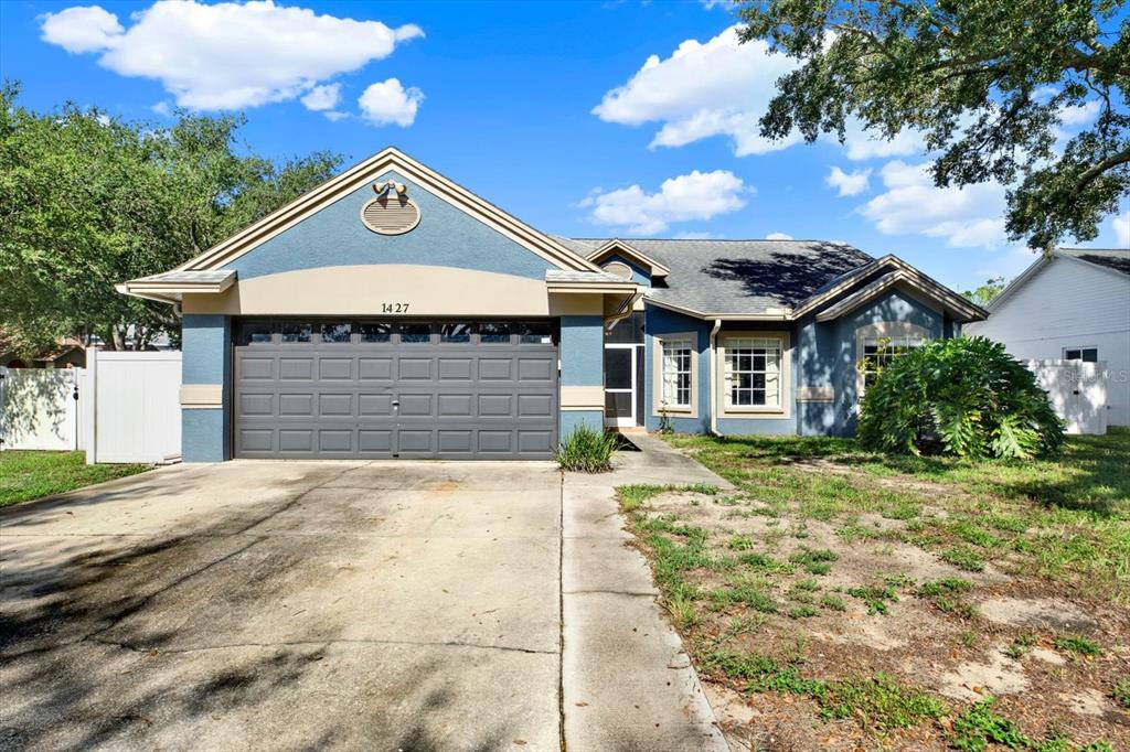 A blue single-story house with a two-car garage and a white vinyl fence — 1427 BAY VIEW STREET, TARPON SPRINGS, FL