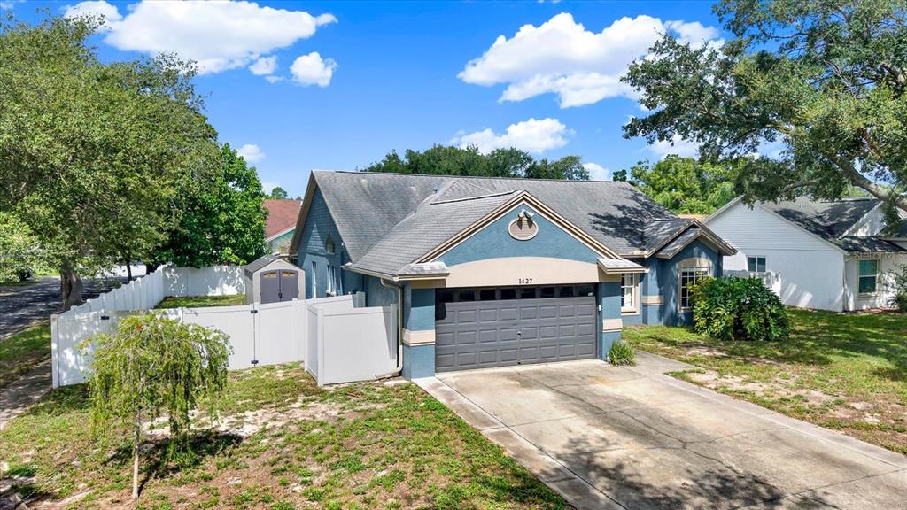 A blue single-story house with a two-car garage and a white vinyl fence — 1427 BAY VIEW STREET, TARPON SPRINGS, FL