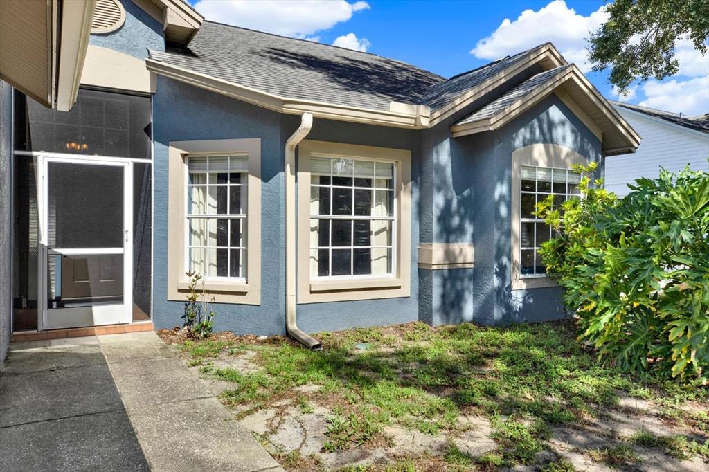 A blue house exterior features a screened front door, three windows, and a patchy lawn — 1427 BAY VIEW STREET, TARPON SPRINGS, FL