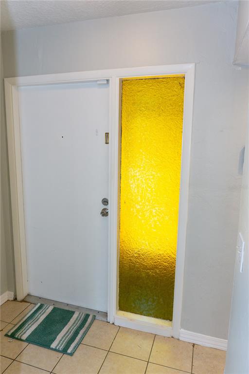 A white front door sits next to a tall, yellow textured glass sidelight window — 603 SW 75TH STREET UNIT 104, GAINESVILLE, FL