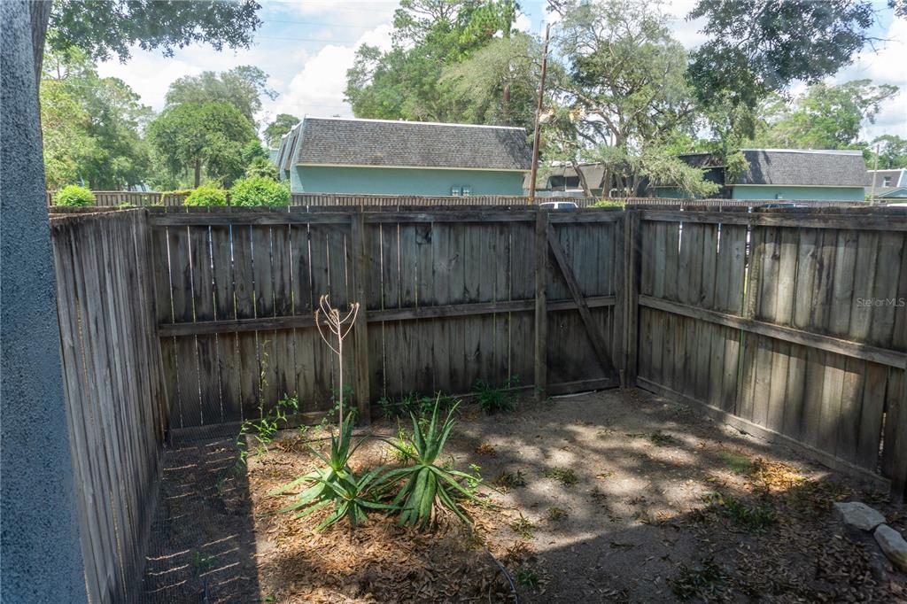 A small, fenced-in backyard features two aloe plants in a patch of dirt — 603 SW 75TH STREET UNIT 104, GAINESVILLE, FL
