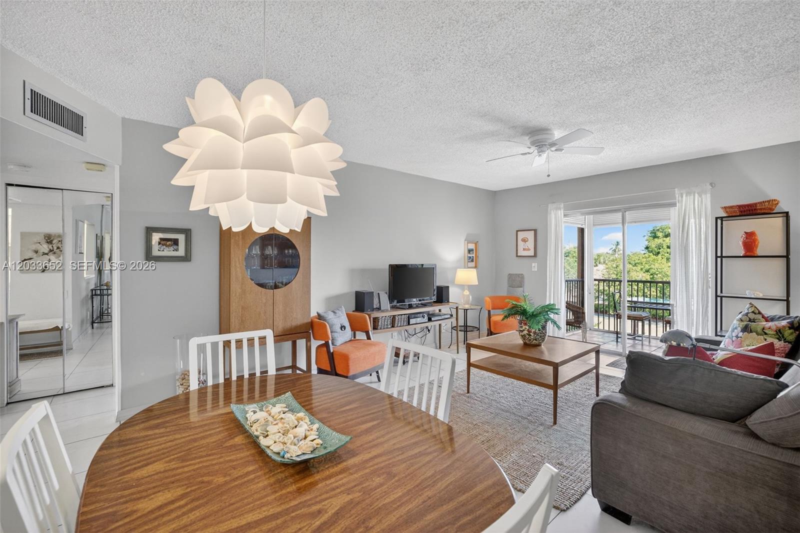 A living and dining area features a large pendant light, wooden furniture, and balcony access — 257 S Cypress Rd # 436, Pompano Beach FL 33060, POMPANO BEACH, FL