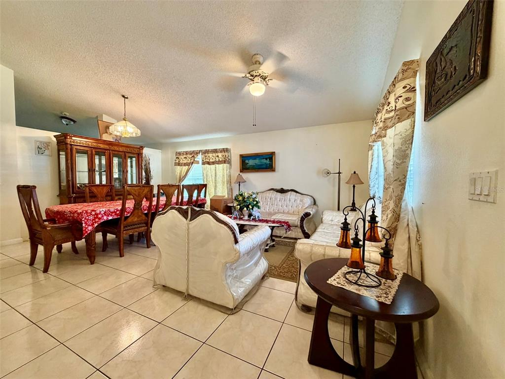 A combined dining and living area features tile flooring, a ceiling fan, and traditional furniture — 2319 LILY PAD LANE, KISSIMMEE, FL