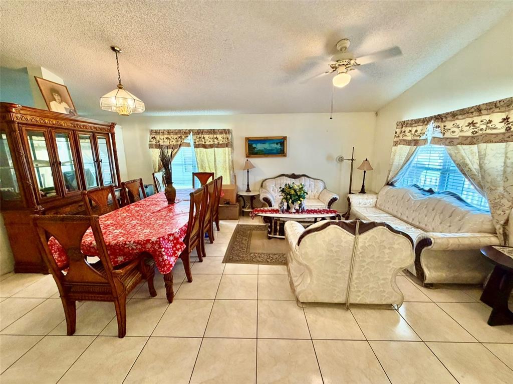A dining and living area features tile flooring, a large wooden hutch, and upholstered furniture — 2319 LILY PAD LANE, KISSIMMEE, FL