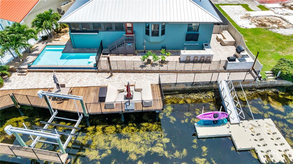 An aerial view shows a teal house with a pool, patio, and private boat dock — 5004 ENSIGN LOOP, NEW PORT RICHEY, FL