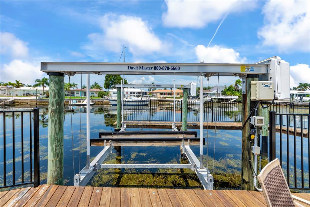 A boat lift stands over a canal with houses visible in the background — 5004 ENSIGN LOOP, NEW PORT RICHEY, FL