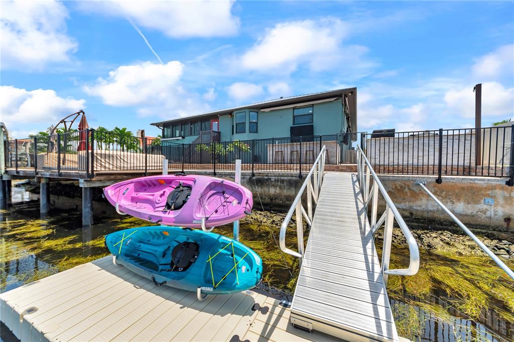 A teal house with a dock, a metal ramp, and two kayaks sits by the water — 5004 ENSIGN LOOP, NEW PORT RICHEY, FL
