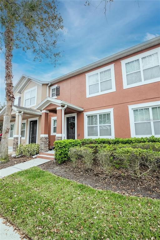 A two-story townhouse exterior features tan and orange stucco walls with white-trimmed windows — 10184 HARTFORD MAROON ROAD, ORLANDO, FL