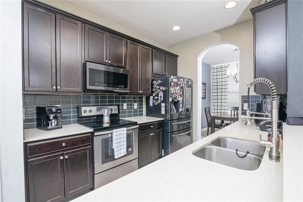 A kitchen features dark wood cabinets, stainless steel appliances, and a white countertop — 10184 HARTFORD MAROON ROAD, ORLANDO, FL