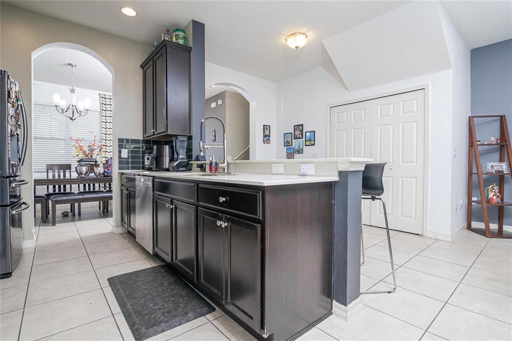 A kitchen features dark wood cabinets, stainless steel appliances, and a breakfast bar with seating — 10184 HARTFORD MAROON ROAD, ORLANDO, FL