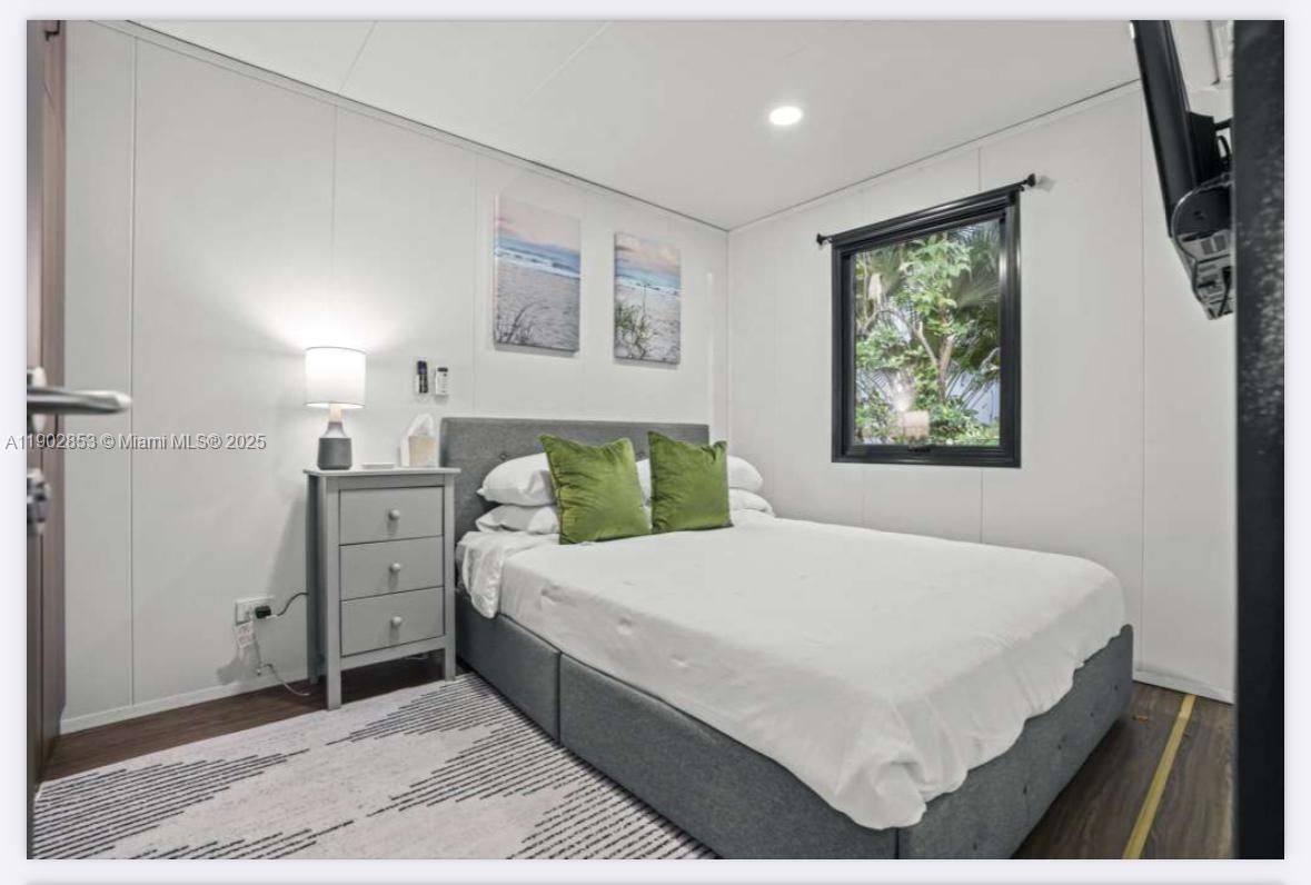 A bedroom features a gray bed, a matching nightstand, two beach paintings, and a window — 3460 70th Avenue NE, Naples FL 34120, NAPLES, FL