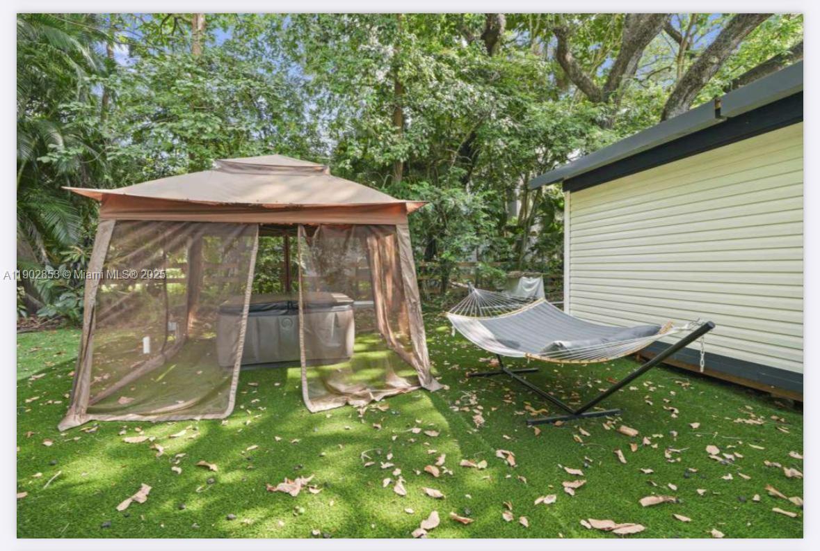 A backyard features a gazebo with a hot tub, a hammock, and artificial grass — 3460 70th Avenue NE, Naples FL 34120, NAPLES, FL