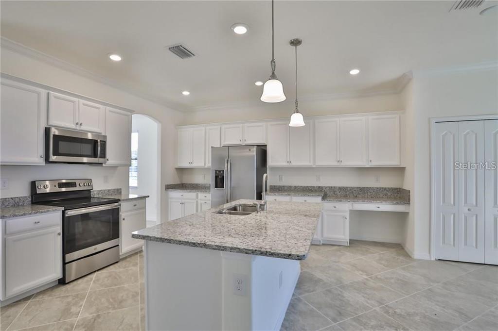An empty room with light-colored tile flooring, white walls, and an arched entryway — 11424 SWEETGRASS DRIVE, BRADENTON, FL