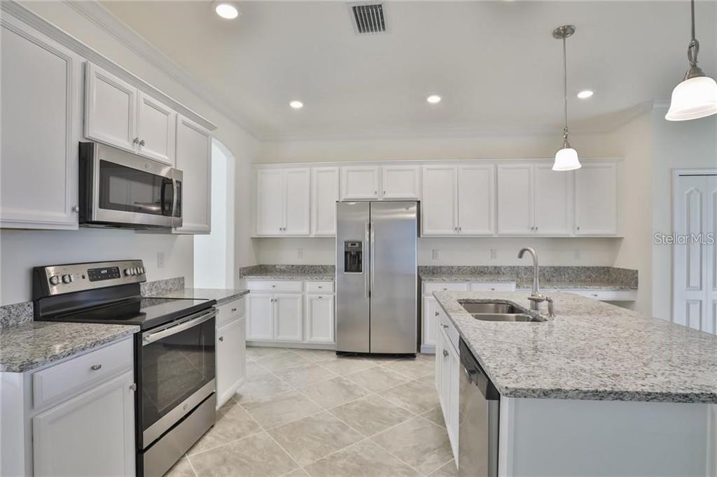 A kitchen with white cabinets, granite countertops, stainless steel appliances, and a central island — 11424 SWEETGRASS DRIVE, BRADENTON, FL