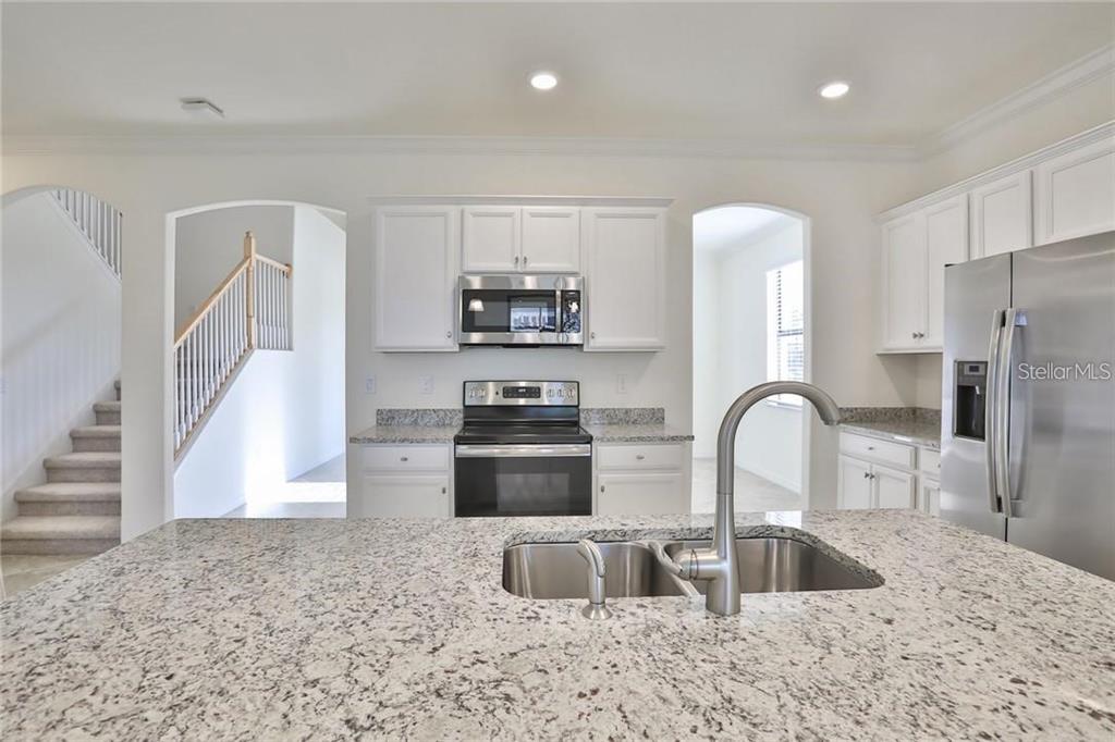 A kitchen with white cabinets, granite countertops, stainless steel appliances, and a central island — 11424 SWEETGRASS DRIVE, BRADENTON, FL