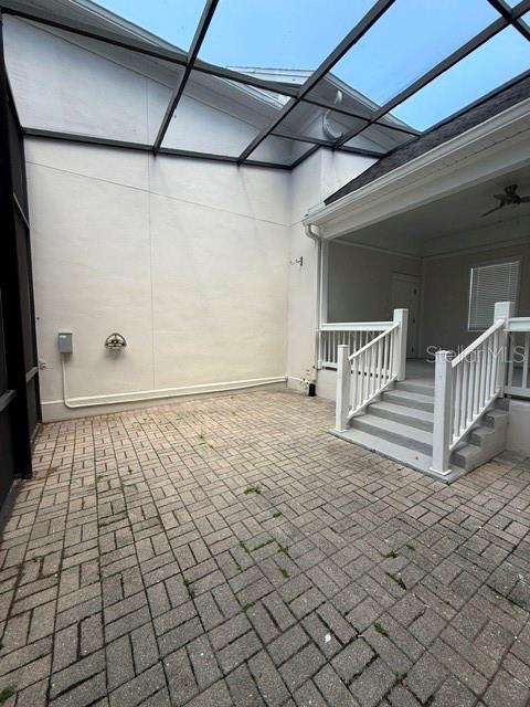 A screened-in patio features a paved floor and a white staircase leading to a doorway — 912 WATERSIDE DRIVE, CELEBRATION, FL