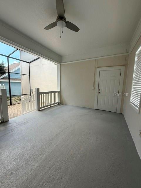 A covered patio features a gray concrete floor, a ceiling fan, and a white door — 912 WATERSIDE DRIVE, CELEBRATION, FL