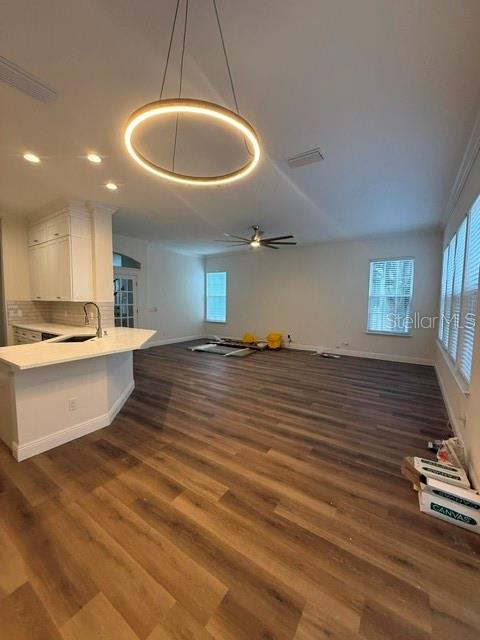 An open-concept kitchen and living area feature wood-look flooring and a modern circular pendant light — 912 WATERSIDE DRIVE, CELEBRATION, FL