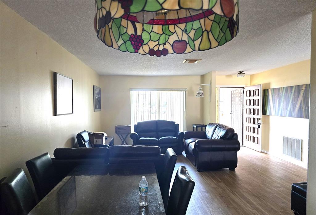A living and dining area features dark leather furniture, a stained-glass chandelier, and wood-look flooring — 10641 TIMBER LANE, PORT RICHEY, FL