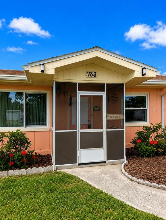 The exterior of a house features a screened-in front porch and a concrete walkway — 733 LAUREL AVENUE, VENICE, FL