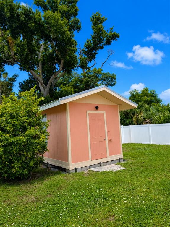 A peach-colored shed with a single door sits on a grassy lawn — 733 LAUREL AVENUE, VENICE, FL
