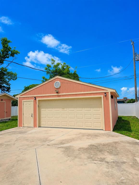 A peach-colored detached garage with a white roll-up door and a side entry door — 733 LAUREL AVENUE, VENICE, FL