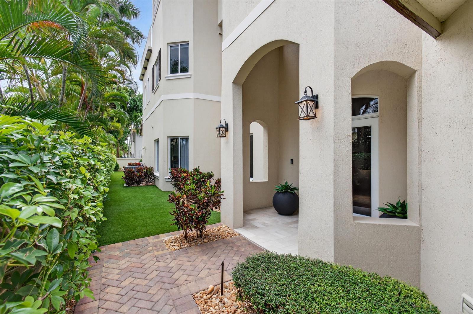 A paved walkway leads to a covered entryway of a beige stucco house with landscaping — 1942 NE 6th Street # C, Deerfield Beach FL 33441, DEERFIELD BEACH, FL