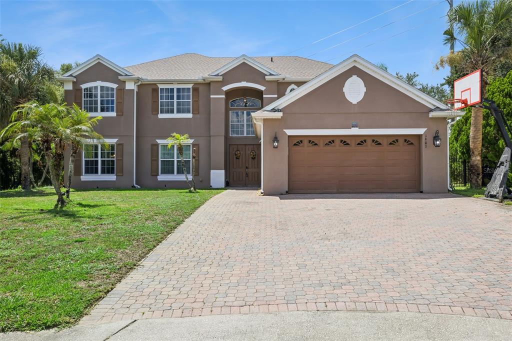 A two-story house with a brown stucco exterior, a paved driveway, and a basketball hoop — 1603 JOHNS COVE LN, OAKLAND, FL