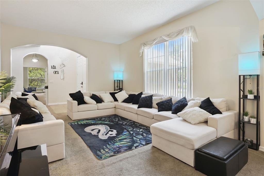 A living room features a large white sectional sofa, a patterned rug, and arched doorways — 1603 JOHNS COVE LN, OAKLAND, FL