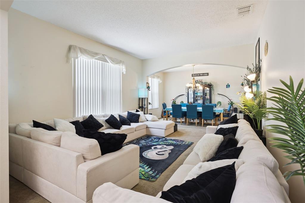 A living room with a large sectional sofa leads to a dining area under an archway — 1603 JOHNS COVE LN, OAKLAND, FL