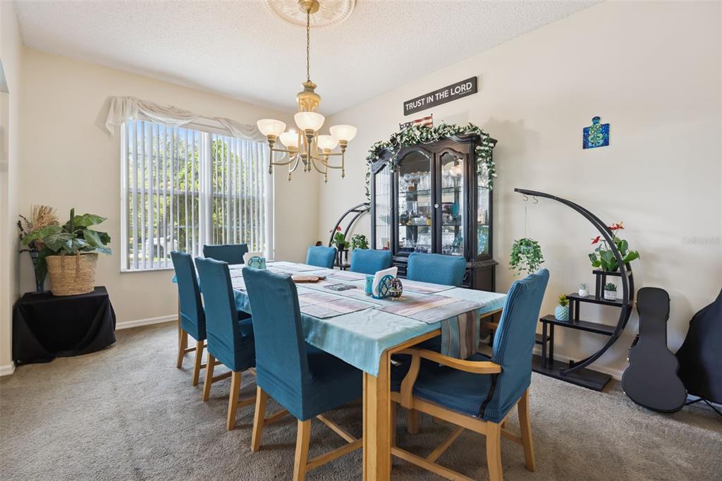 A dining room features a wooden table, blue chairs, a hutch, and a chandelier — 1603 JOHNS COVE LN, OAKLAND, FL