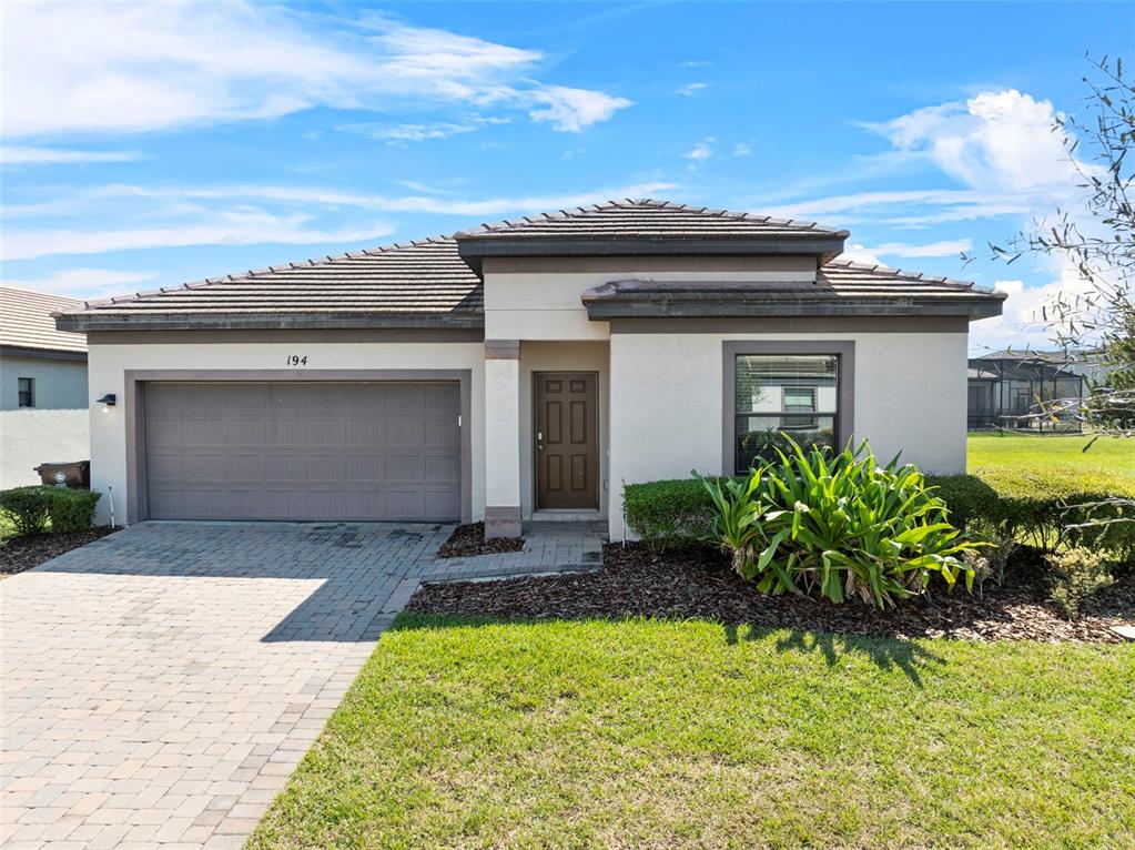 A single-story house with a beige stucco exterior, a tile roof, and a two-car garage — 194 AIDANS LANDING, HAINES CITY, FL