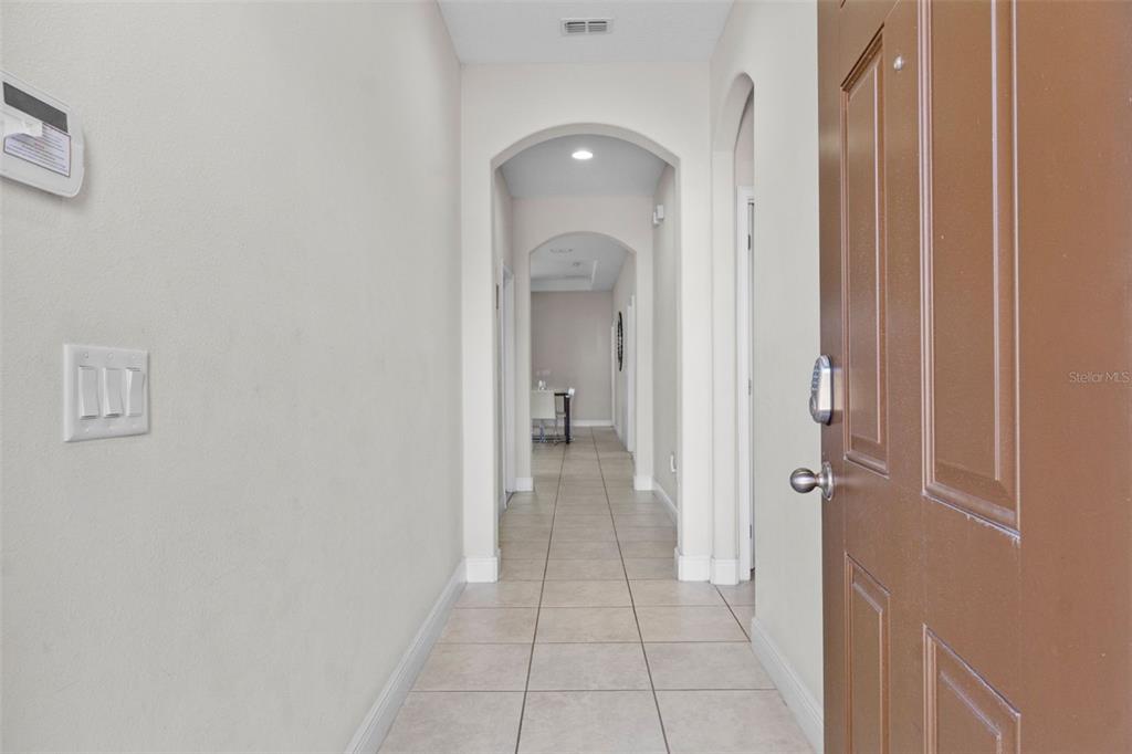 A view from an open brown door into a tiled hallway with arched entryways — 194 AIDANS LANDING, HAINES CITY, FL