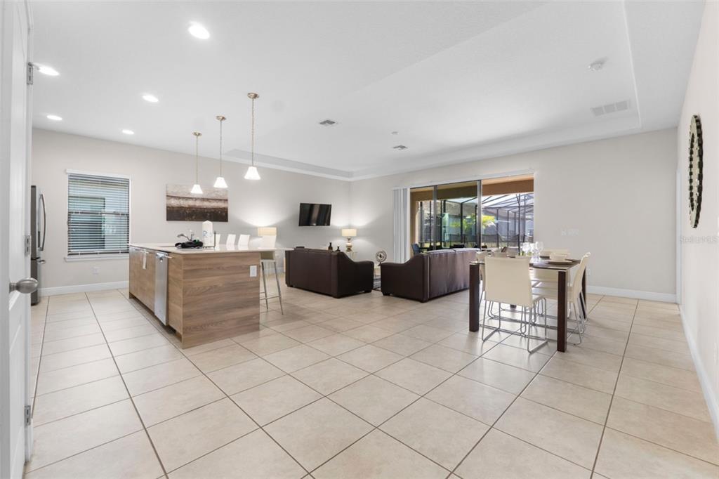 An open-concept living area features a kitchen island, dining table, and tile flooring — 194 AIDANS LANDING, HAINES CITY, FL