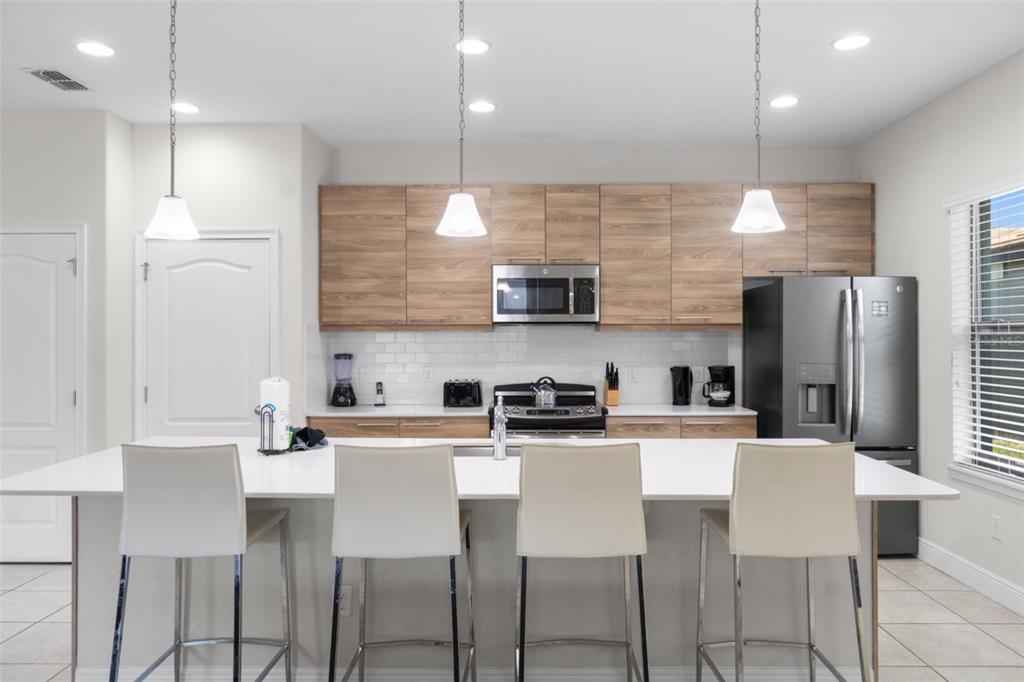 A modern kitchen features a large white island with bar seating and wood-grain cabinetry — 194 AIDANS LANDING, HAINES CITY, FL