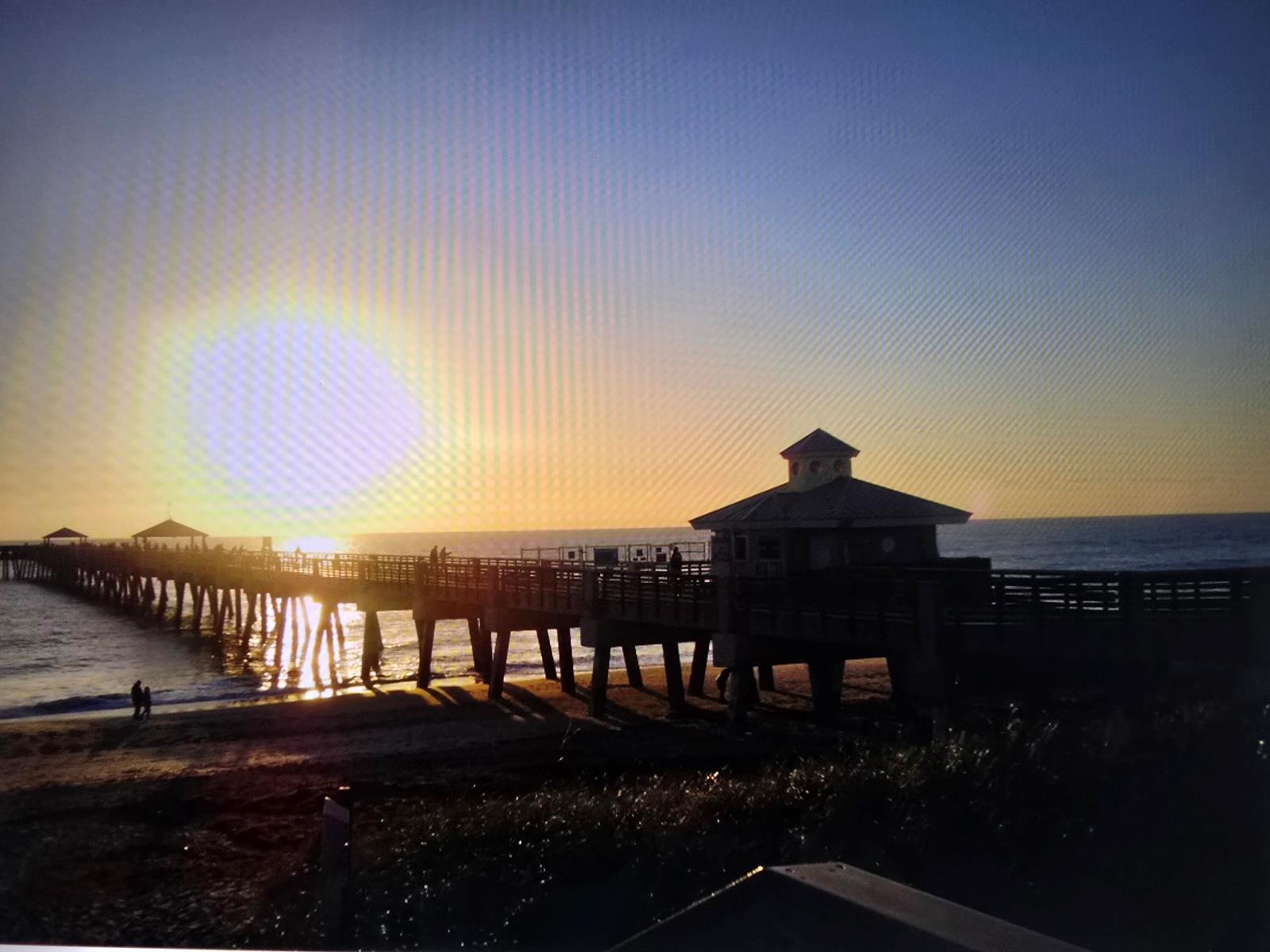 A long wooden pier extends into the ocean during a bright sunset — 420 Celestial Way # 204, Juno Beach FL 33408, JUNO BEACH, FL
