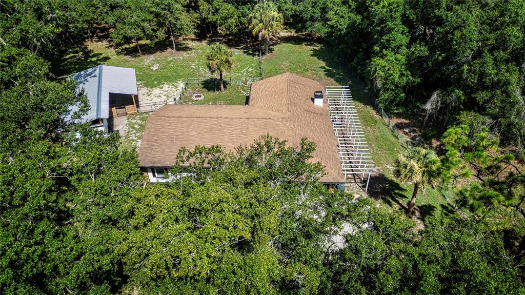 An aerial view shows a house with a brown roof, a pergola, and a detached carport — 3309 YELLOWKNIFE CIRCLE, WIMAUMA, FL