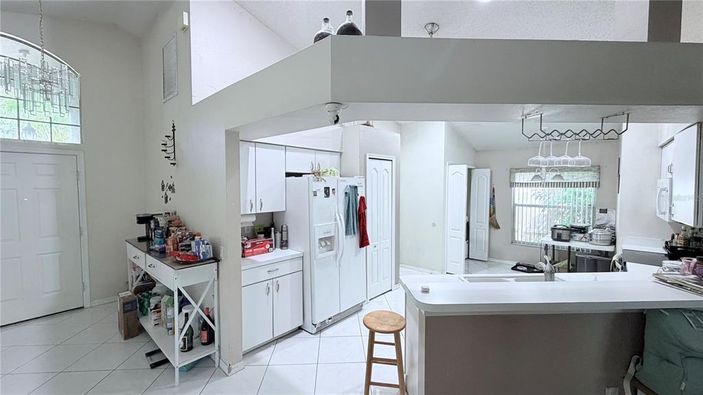 A kitchen with white cabinets, a breakfast bar, and tile flooring opens to an entryway — 8503 PRINGLE WAY, TAMPA, FL
