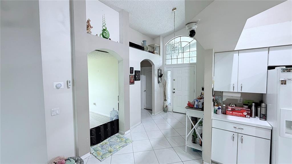 A tiled entryway leads to a white front door, an arched doorway, and kitchen cabinets — 8503 PRINGLE WAY, TAMPA, FL